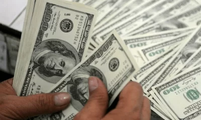 Dollar Gains, Stocks Slip as Fed Officials Talk tough on Rates